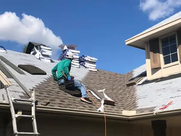 Worker replacing shingles on roof